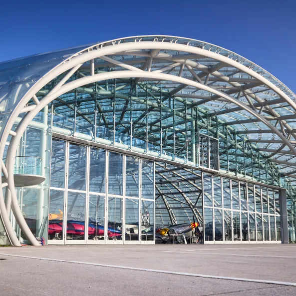 Außenansicht des Hangar-7 mit geöffnetem Tor, Blick auf Ausstellungsbereich mit mehreren Exponaten
