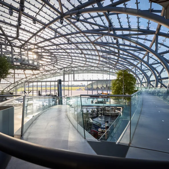  Innenansicht des Hangar-7 mit Glas-Stahl-Architektur und einem Gehweg über den Ausstellungsbereich