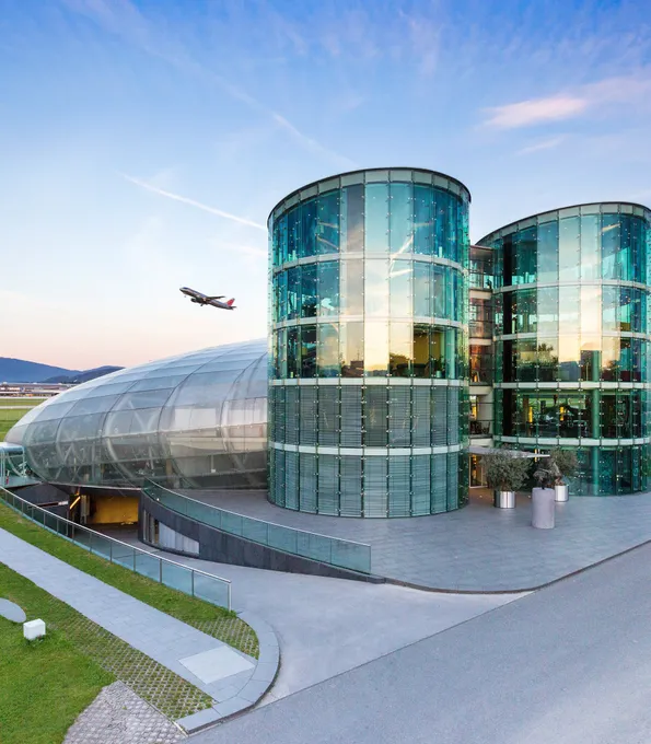 outside shot of Hangar-7 with an airplane in the sky 